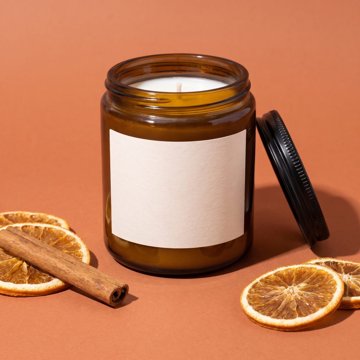 Amber candle jar on a terracotta backdrop with dried orange slices
