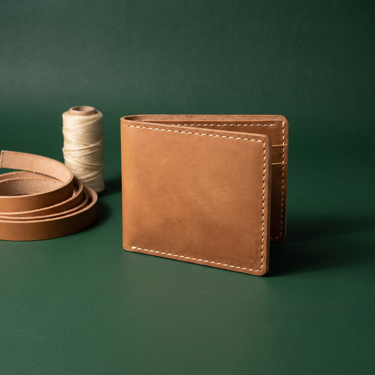 Tan leather wallet standing open on a forest green backdrop